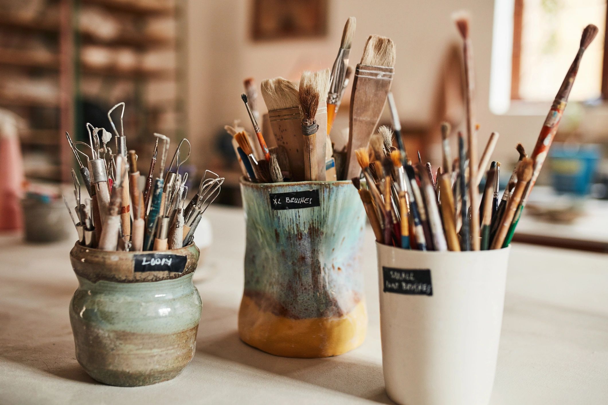 Paint brushes and art supplies in jars on a studio table